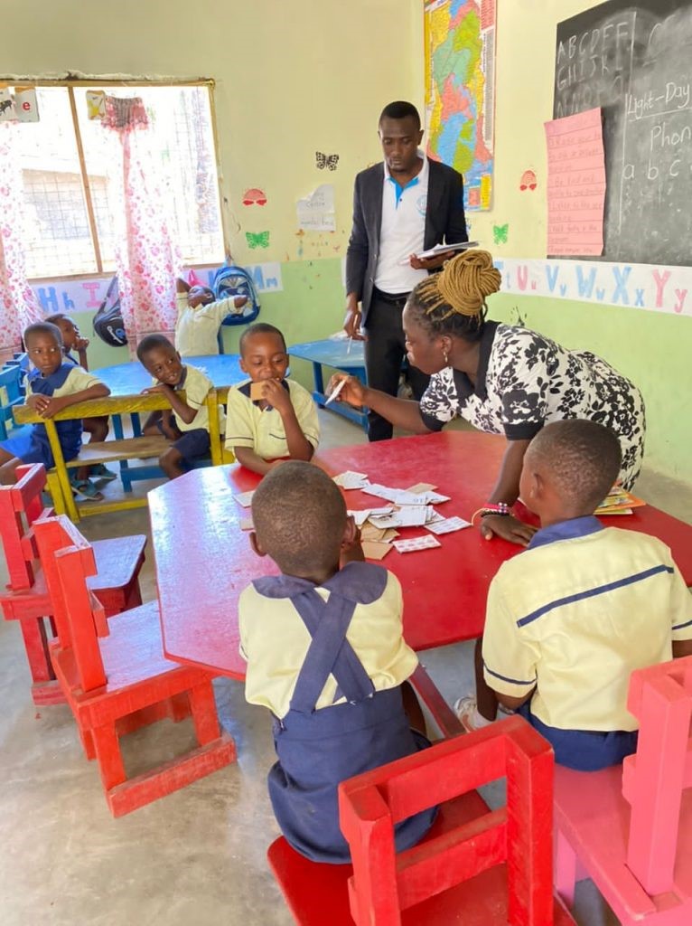 Two teachers and several children in a classroom learning through play. 